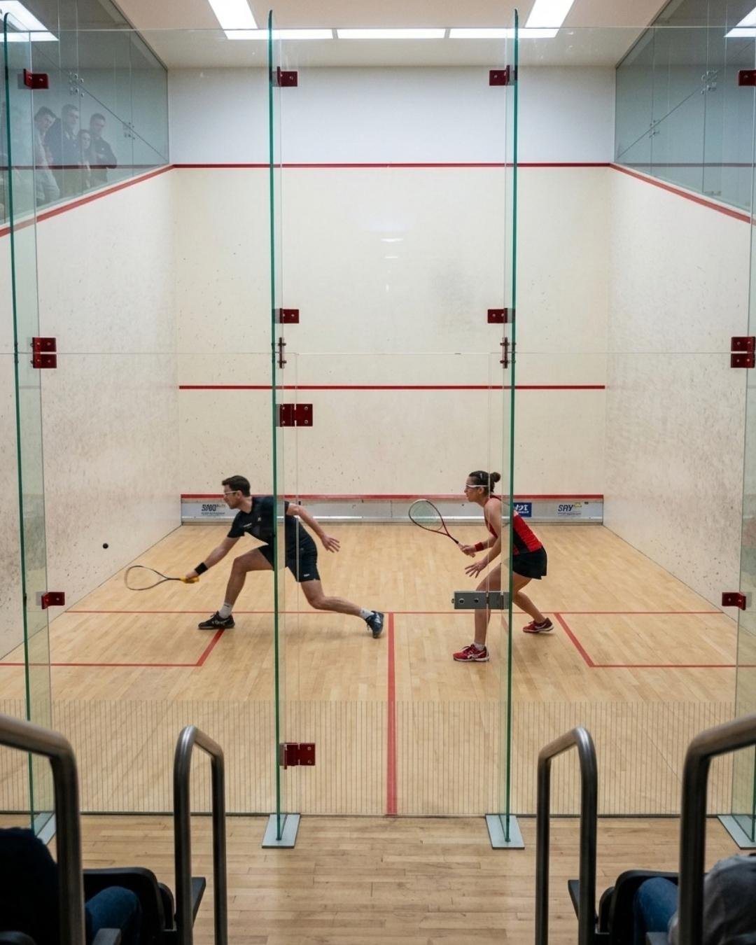 Ein Squash-Ballwechsel durch die Glasrückwand gesehen — Illustration der BetterSport-Seite für Squash-Clubs