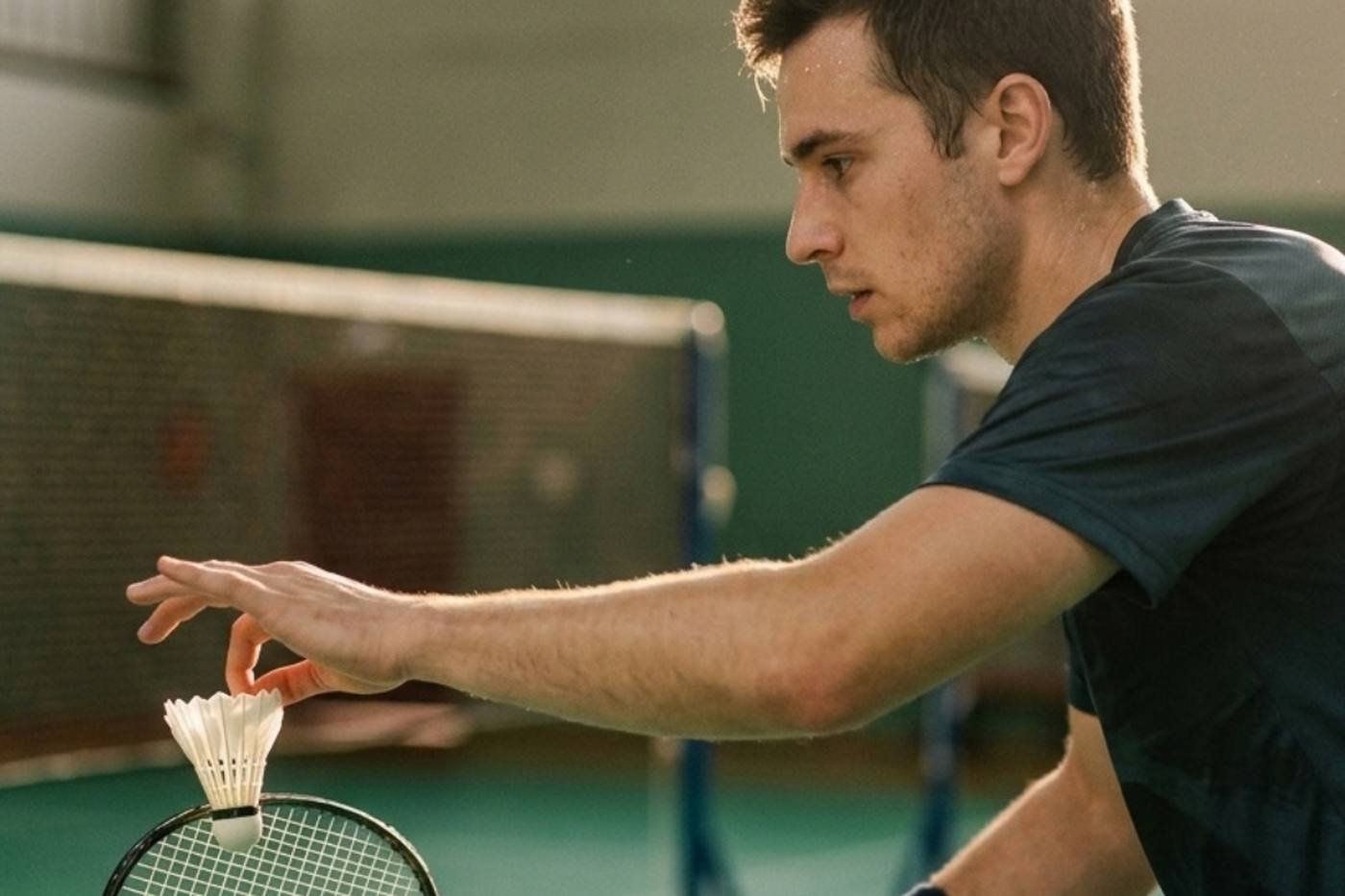 Ein Badmintonspieler beim Aufschlag, den Federball in der Hand — Website-Erstellung für Badminton-Trainer